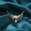 Soar with elegance wearing this Angel Wing Brooch, featuring delicate enamel, a radiant pearl, and a teardrop stone for a heavenly touch