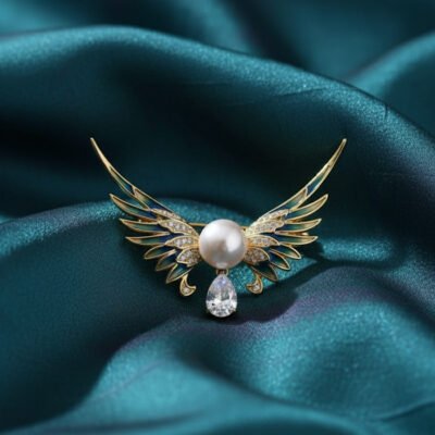 Soar with elegance wearing this Angel Wing Brooch, featuring delicate enamel, a radiant pearl, and a teardrop stone for a heavenly touch